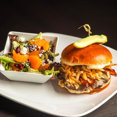The Farmer Burger served on a white plate with a bowl of Chef's house salad.