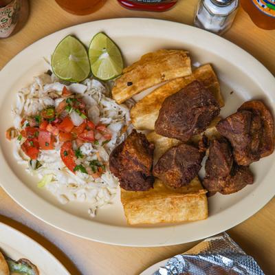 Fried pork served with yuca, lime wedges, and cabbage salad.