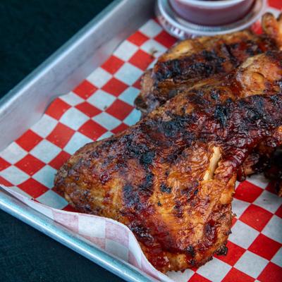 Roasted chicken served on a tray with a dipping sauce.