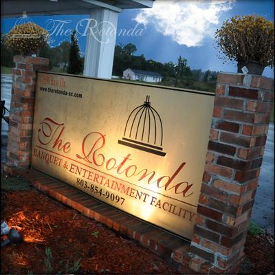 A gold-lit banquet facility sign for the Rotonda flanked by two brick pillars.