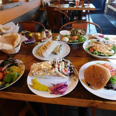 A wooden table is filled with various Mediterranean dishes.