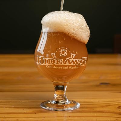 Beer being poured into a glass with Hideaway logo.