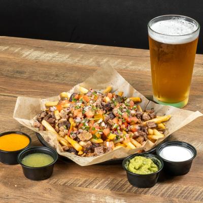 plate of carne asada fries, with beer and 4 sides of sauce.