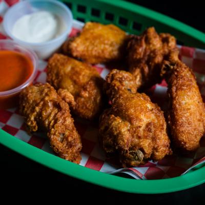 Basket of fried chicken wings with dipping sauces.