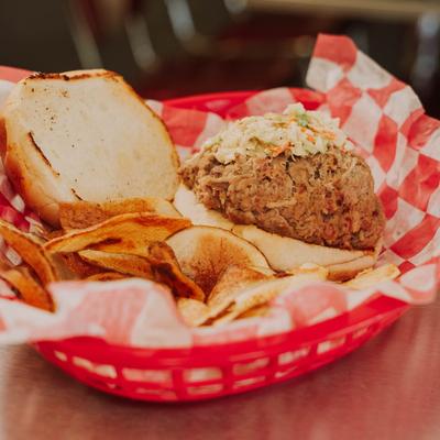 Pulled pork sandwich, with BBQ sauce, coleslaw, and potato chips.