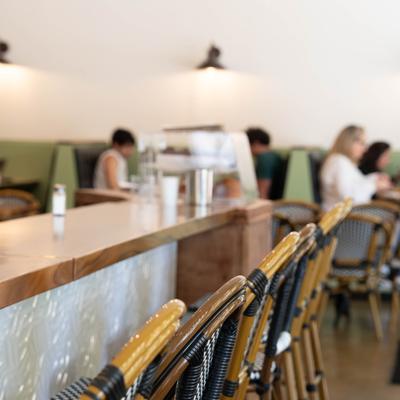 Bar chairs line along the counter with people in the blurred background.