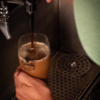 A person pouring a glass of beer from a tap at a bar.