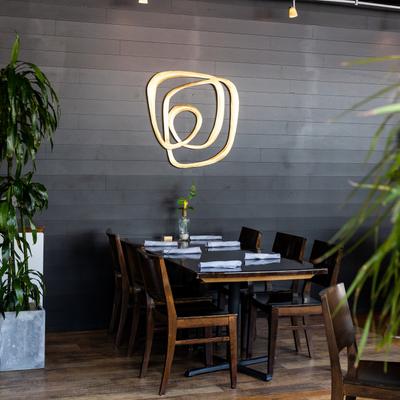 Interior, a set dining table by a black wall with curvy light sculpture decoration