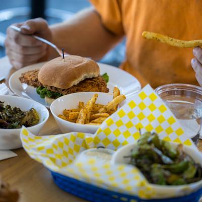Fried chicken sandwich with fries and sides on a table.