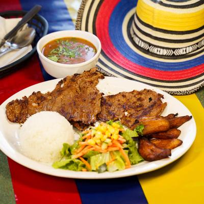 Grilled steak, served with white rice, beans, fried plantain, and salad.