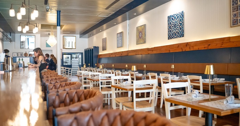 Cozy restaurant interior, dining area, and bar with guests sitting at the bar counter