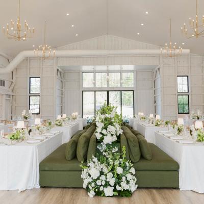 Elegant wedding reception tables with olive-green central banquette seating banked and lush flowers.