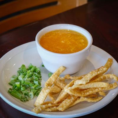 Chicken broth with an egg stirred in, chopped scallions and wonton strips.