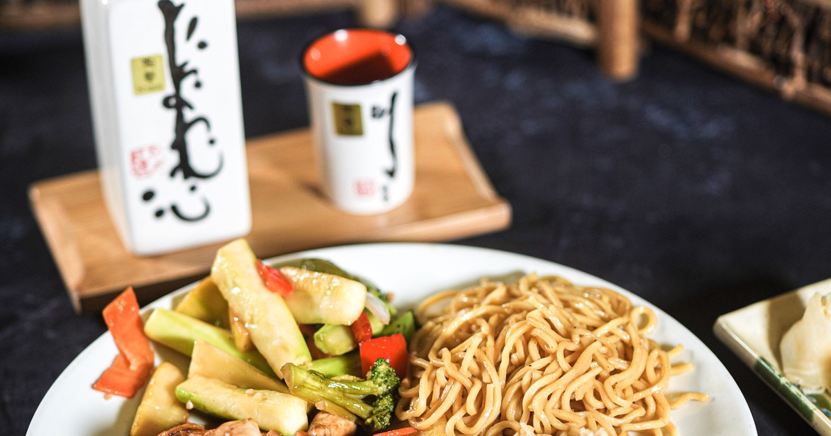 Hibachi meal featuring grilled chicken, stir fried vegetables, noodles and rice