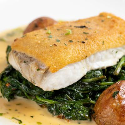 Halibut over sauteed spinach with oven roasted potatoes and creamy sauce.
