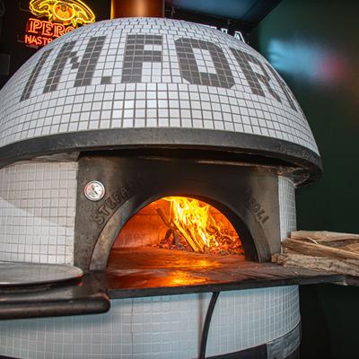 Wood-fired pizza oven featuring a white tiled exterior and a handcrafted design.