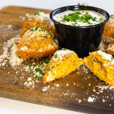 Jalapeno popper toasted ravioli served with a sauce for dipping.