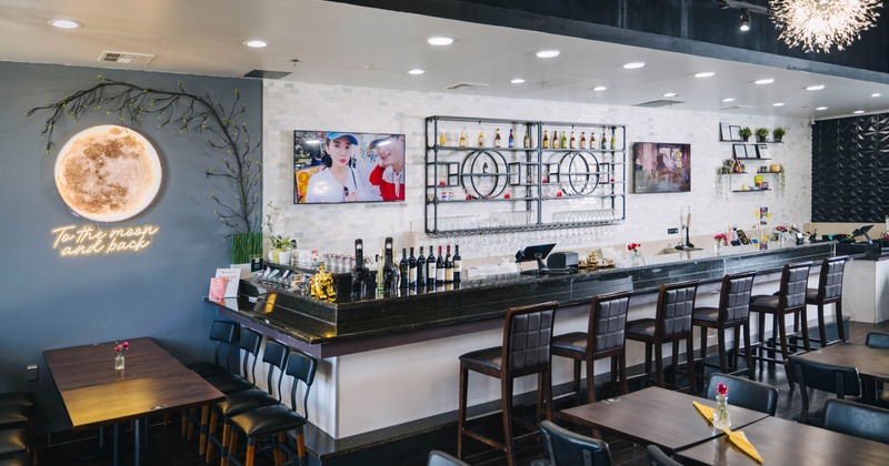 Interior, bar and seating area, wooden top bar with stools, table for eight on the left