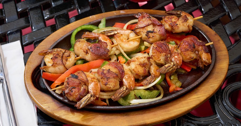 Shrimp with peppers onions and lime on sizzling skillet