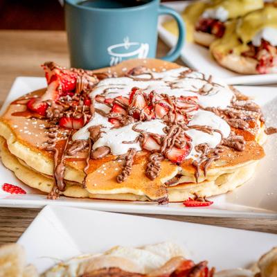 Mega pancake plate with nearby teal coffee mugs and food plates.