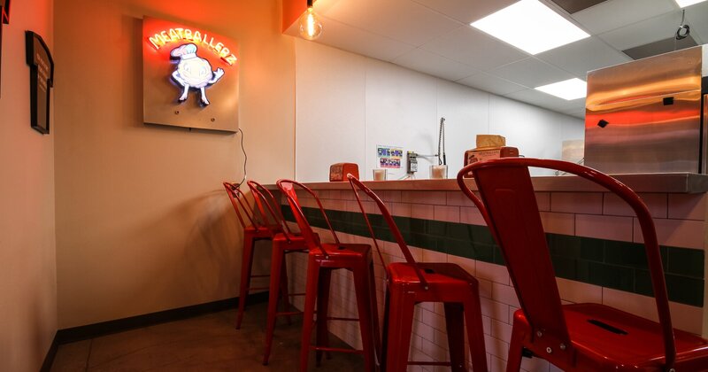 Interior, bar counter with tall red chairs, light sign board on the wall
