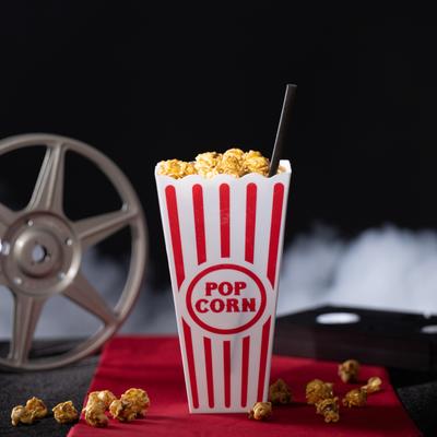 A striped popcorn container filled with Get Poppin cocktail sits on a red cloth.