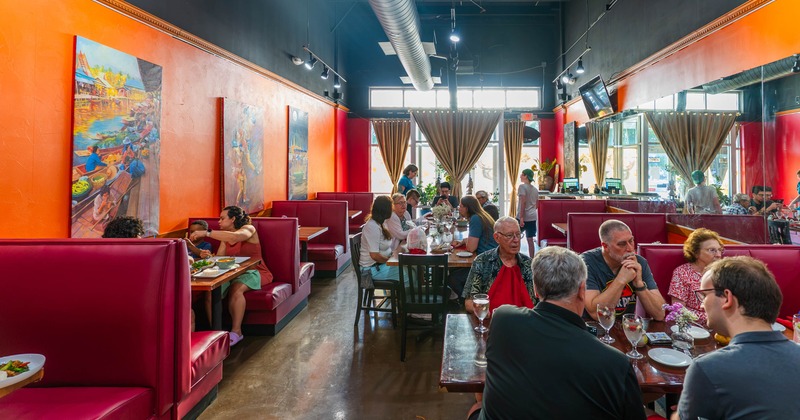Interior featuring red booths, vibrant orange walls and large, colorful artwork