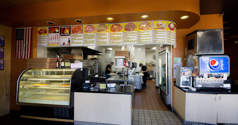 Interior of the restaurant with a counter and a pizza oven in the background