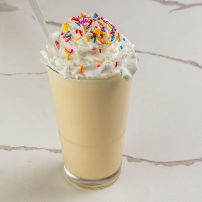 Milkshake topped with whipped cream and colorful rainbow sprinkles.
