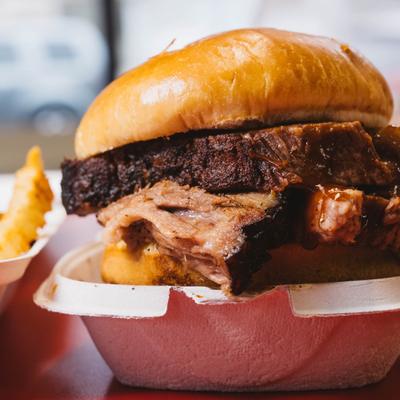 A close-up of a brisket sandwich with a side of fries.
