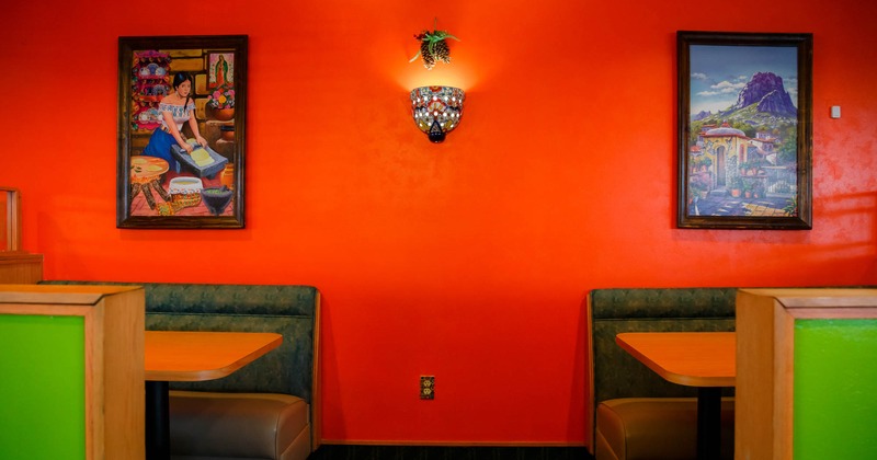 Two booths along the wall with paintings