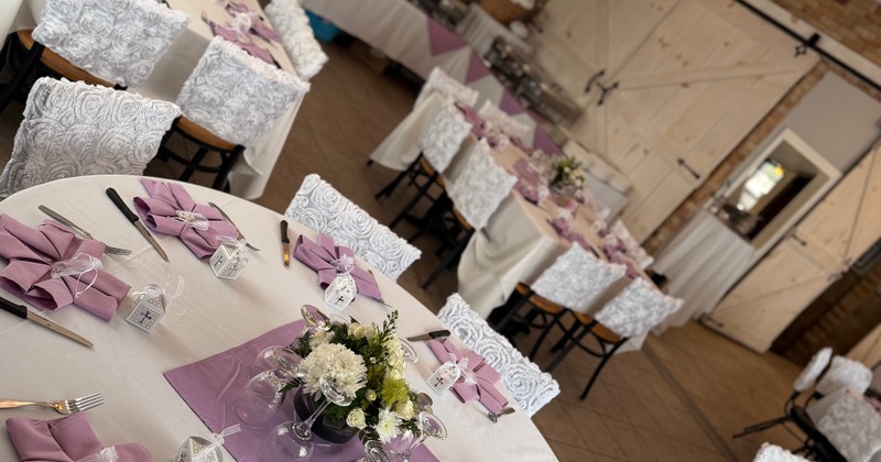 Fully set tables with floral centerpieces and purple napkins