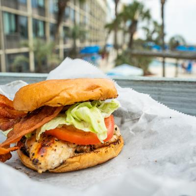 Chicken sandwich served on a bun with crispy bacon, lettuce and tomato.