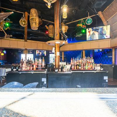 Bar area with liquor bottles and tropical decor.