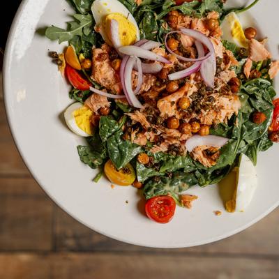 Salad with greens, boiled egg, cherry tomato and red onion, top view.