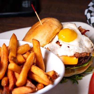 Bacon cheeseburger topped with a fried egg and served with fries.