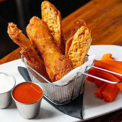 Buffalo chicken egg rolls with Buffalo sauce, blue cheese sauce, and carrots.