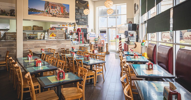 Order counter, dining tables in the middle, high back seating with tables and chairs by windows