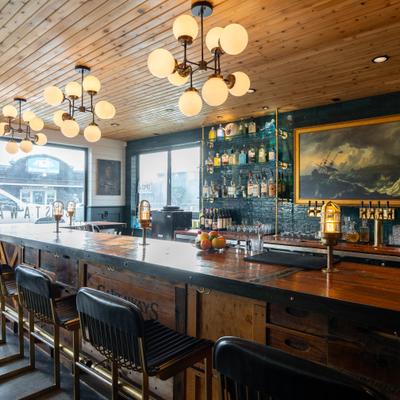 Interior with a wooden bar, industrial-style lighting and a well-stocked bar shelves.