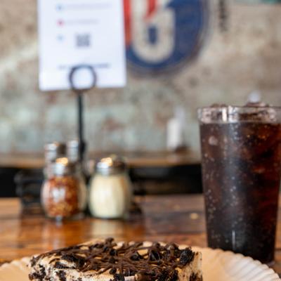 Oreo bar served on a white paper plate, accompanied with a soft drink.
