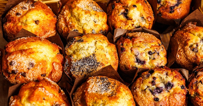 Close-up of assorted muffins in brown wrappers in a wicker basket