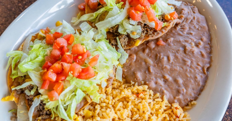 Ground beef tacos, with lettuce, tomato, rice, and beans