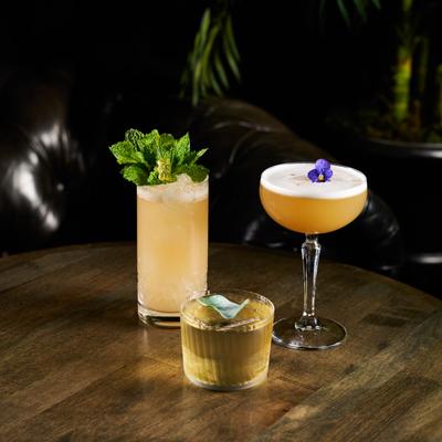 Three cocktails on a wooden table, Mind Body & Spirits, Goose Chase, Book of Wei.