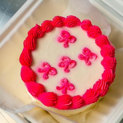 Mini bento cake featuring hot pink piped bows and star border decoration.