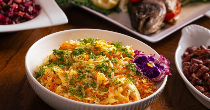 A bowl of shredded cabbage salad topped with fresh dill