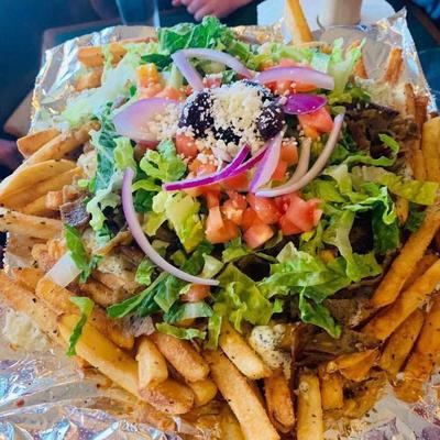 Loaded Greek-style fries with lettuce, tomatoes, onions, feta cheese, and olives.