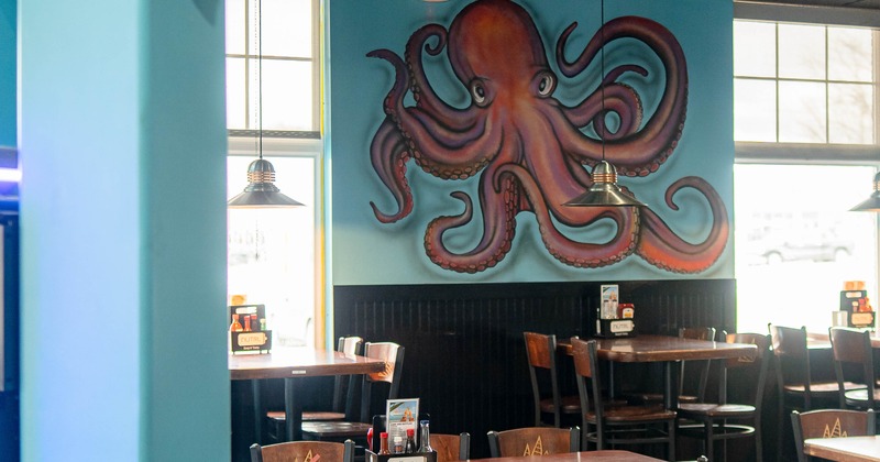 Interior, wooden tables and chairs and octopus mural on the wall