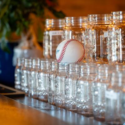 Decorative arrangement with a baseball resting atop a stack of clear glass jars.