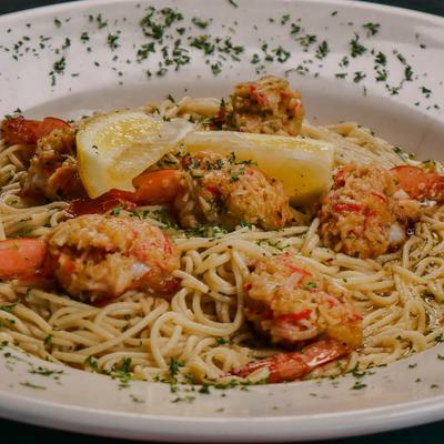 Seafood pasta with shrimp, lemon wedges, and herbs.