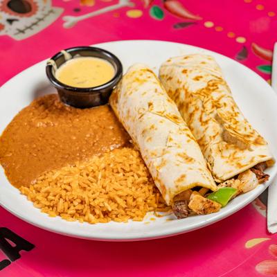 Two shrimp tacos with sidws of rice, beans and a dip.